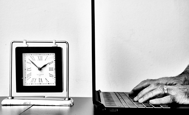 Arbeit am Laptop neben einer Uhr als Symbol für das flexible virtuelle Büro